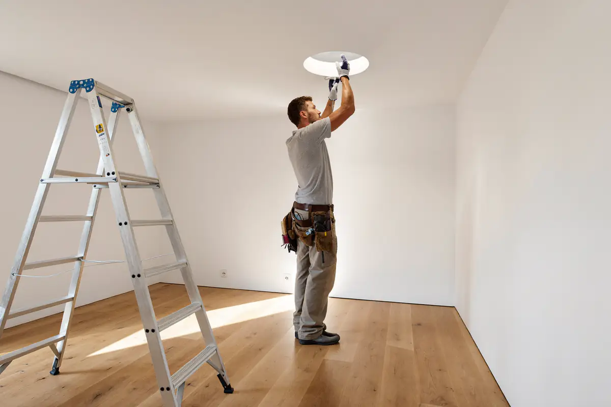 Eletricista a instalar um foco LED no teto de um apartamento