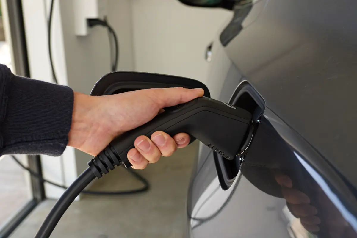 Mão a ligar a ficha de carregamento Tipo 2 na tomada de um carro elétrico